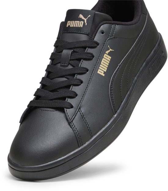 Zwarte sneaker van leer met gouden Puma-logo op de zijkant en tong.
