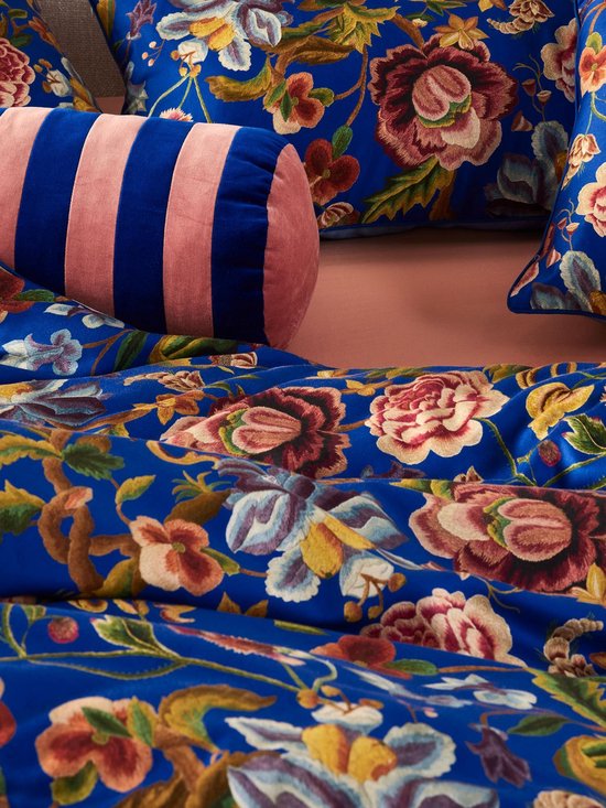 Close-up van blauwe kussens met een gedetailleerde bloemenprint en een roze gestreept rolkussen.