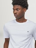 Close-up van een witte T-shirt met korte mouwen en een klein zwart '&' logo op de borst.