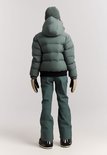 Meisje draagt van achteren gezien een donkergroene, gewatteerde winterjas met capuchon. Ze draagt een groene muts, skibroek en handschoenen.