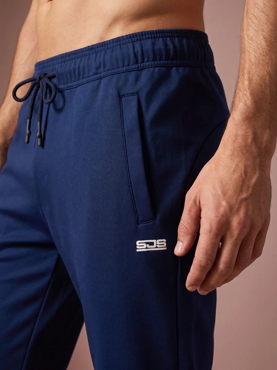 Sluiting van marineblauwe joggingbroek met trekkoord en logo, close-up.