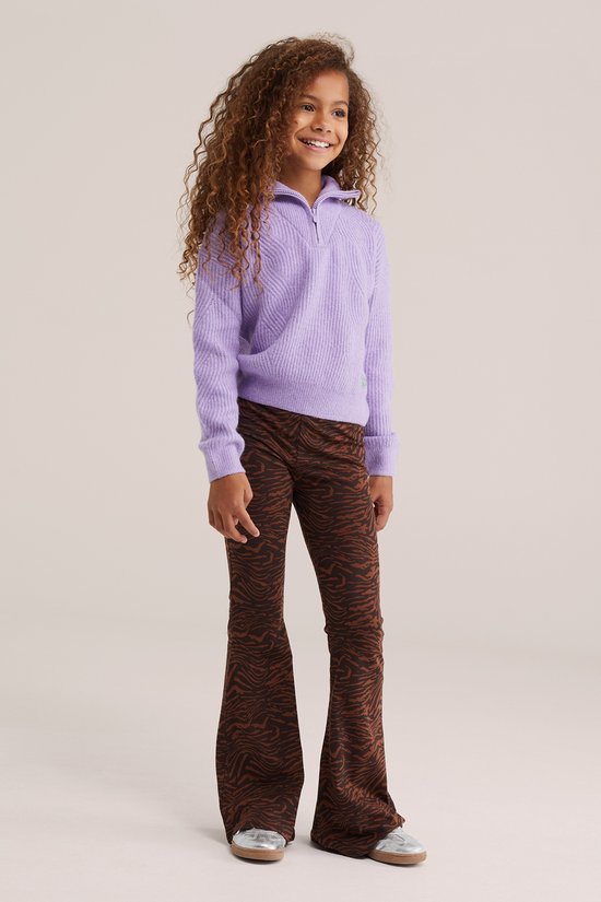 Een meisje met krullend bruin haar draagt een paarse trui en bruine flared broek met zebraprint.
