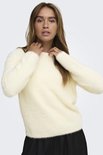 Model met handen bij de hals in een crèmekleurige, pluizige trui.