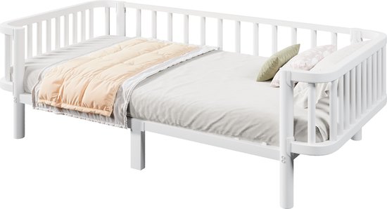Wit metalen dagbed opgemaakt met een beige matras, geel dekbed en sierkussens.