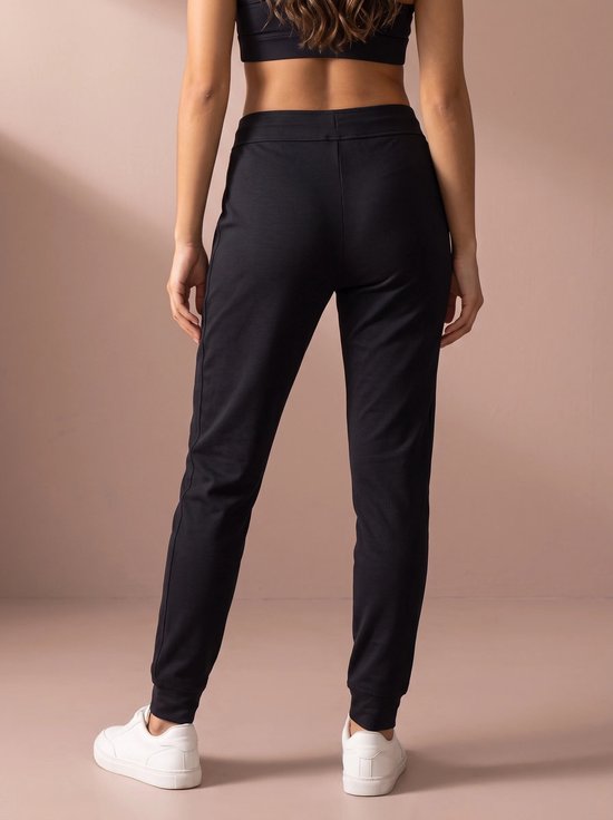 Achterkant van de marineblauwe sportbroek met een elastische tailleband op een model.