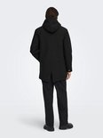 Achterkant van een zwarte parka met capuchon, gedragen door een model met donker haar.
