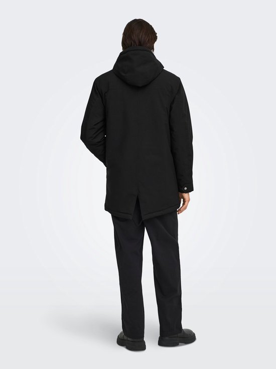 Achterkant van een zwarte parka met capuchon, gedragen door een model met donker haar.