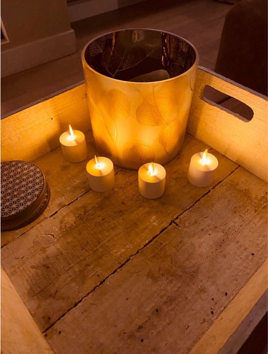 Grote gouden windlicht met bladerpatroon omringd door vier witte led-theelichtjes in een houten kist.