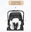 Gedetailleerde weergave van de comfortabele, brede binnenruimte van de zwarte kinderwagen met witte kussens.