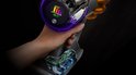 Gouden Dyson V15s Detect stofzuiger met paarse accenten, bediend door een hand. Het scherm toont 9.927.643 deeltjes en 55:37 minuten.