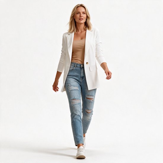 Model loopt in witte blazer met beige top en gescheurde spijkerbroek.