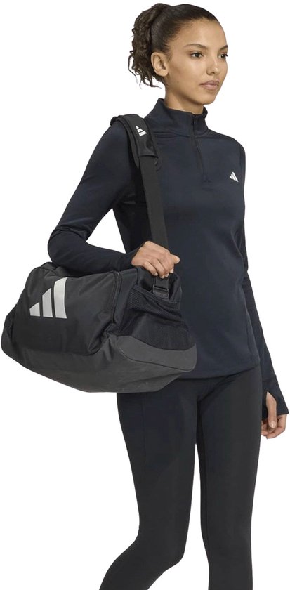 Model draagt een zwart Adidas sportshirt, met een zwarte sporttas over de schouder.
