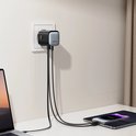 Zwarte 65W-oplader in stopcontact, verbonden met een laptop, tablet en smartphone via kabels.