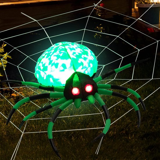 Groene opblaasbare spin met oplichtende rode ogen, geplaatst op een wit spinnenweb in het gras.