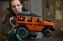 Een vrouw toont de oranje LEGO Technic Mercedes-Benz G 500, met focus op de details.
