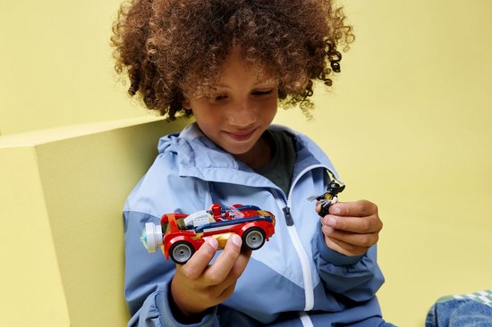 Jongen houdt rode LEGO auto en Wolverine-figuur vast. Spiderman zit in de auto.