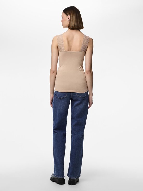 Achteraanzicht van een model in een beige hemdje met kanten bandjes en blauwe jeans.