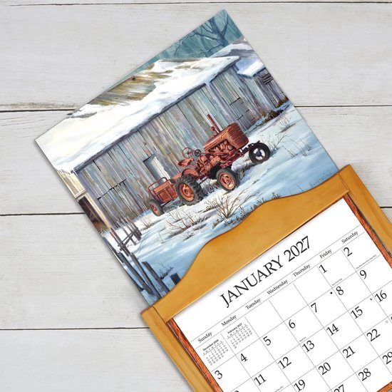 Kalenderpagina voor januari 2027 met een schilderij van een roestige rode tractor in de sneeuw voor een houten schuur, getoond in een kalenderhouder.