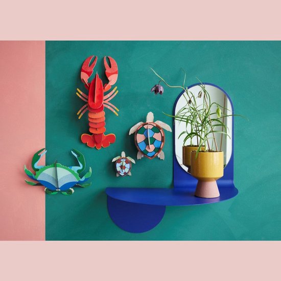 Decoratie van een kreeft, krab en twee schildpadden aan een muur met spiegel en plant.