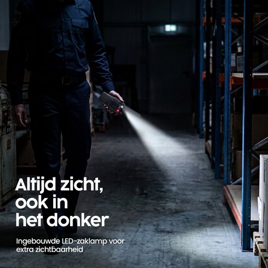 Beveiliger loopt door donker magazijn met ingeschakelde LED-zaklamp op portofoon.