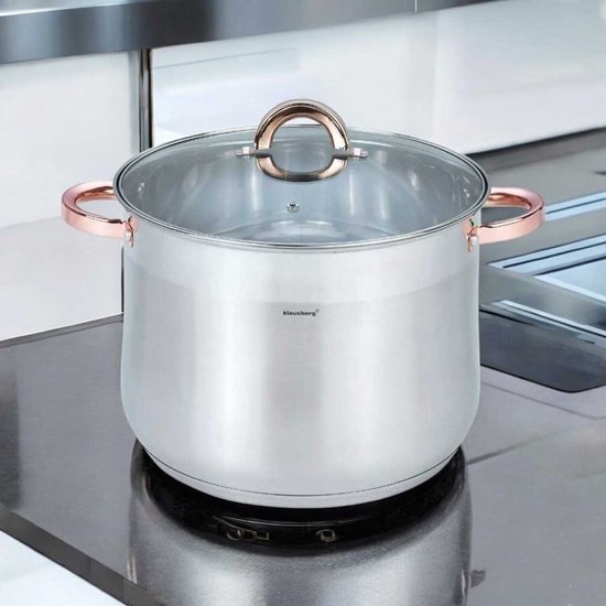 Zilverkleurige soeppan met glazen deksel en koperkleurige handvatten, staand op een kookplaat.
