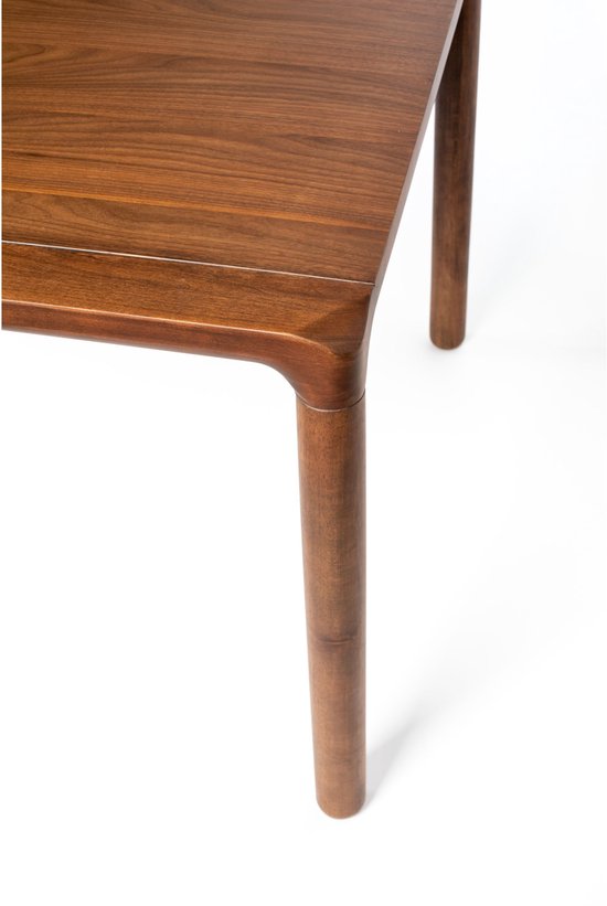 Detail van de bruine walnoot eettafel, met de ronde poot en de afgeronde hoek van het tafelblad.