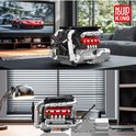 Gedetailleerde V8 motor van LEGO Technic in een woonkamer en op een bureau, naast een tv met raceauto's.