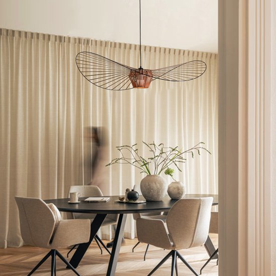 Koperbruine hanglamp in de vorm van een hoed boven een eettafel.