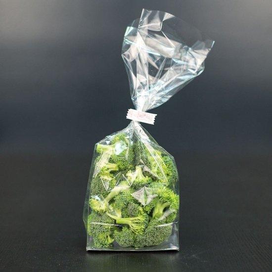 Een zakje met verse broccoliroosjes, tentoongesteld op een donkere achtergrond.