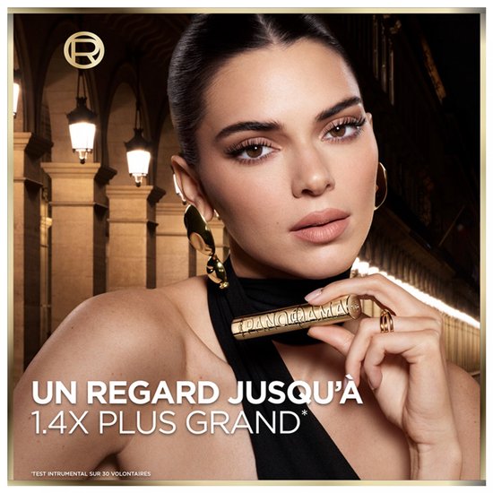 Model houdt gouden mascara huls vast op een stadsplein.