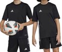Kinderen in zwarte adidas Tabela 23 voetbalshirts en shorts, een jongen houdt een voetbal vast.