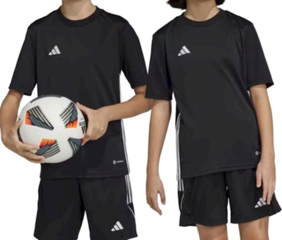 Kinderen in zwarte adidas Tabela 23 voetbalshirts en shorts, een jongen houdt een voetbal vast.
