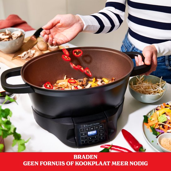 Zwarte multicooker met wokschotel, groenten en chilipepers worden toegevoegd. Geen fornuis of kookplaat nodig.