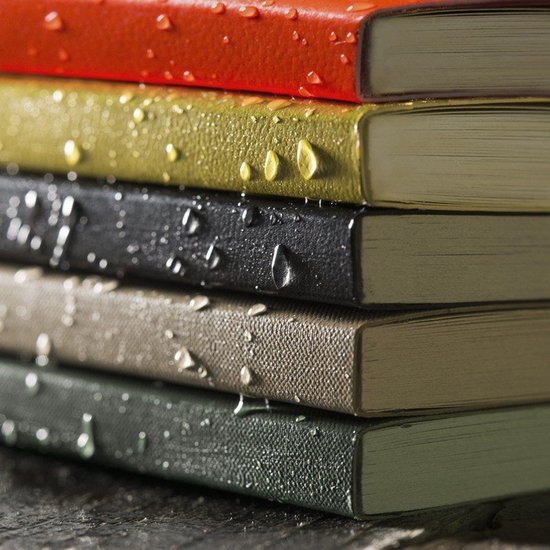 Stapel notitieboeken in verschillende kleuren met waterdruppels op de kaften.