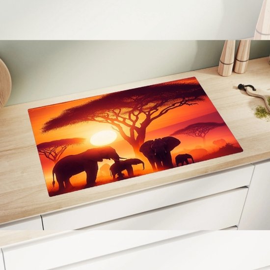 Planche à découper représentant des éléphants au lever du soleil en Afrique sous un grand arbre.
