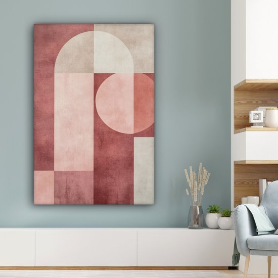 Peinture abstraite rose, beige et blanc avec des formes géométriques accrochée au-dessus d'une armoire blanche dans un salon.