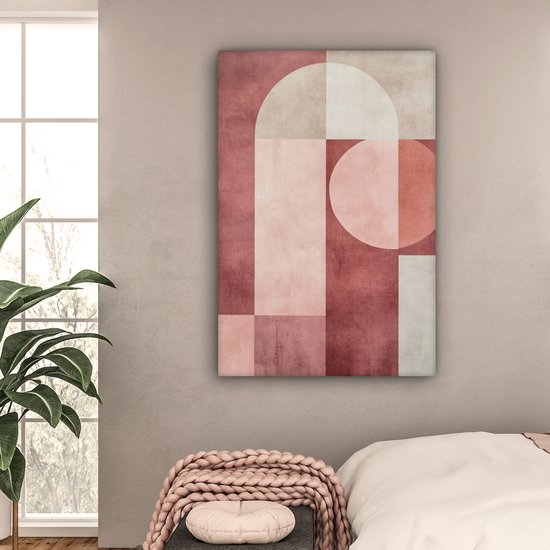 Peinture abstraite rose, beige et blanc avec des formes géométriques accrochée au-dessus d'un lit dans une chambre.