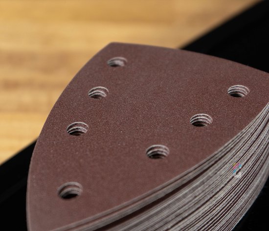 Close-up van een stapel bruin schuurpapier met perforaties, zijkant zichtbaar.