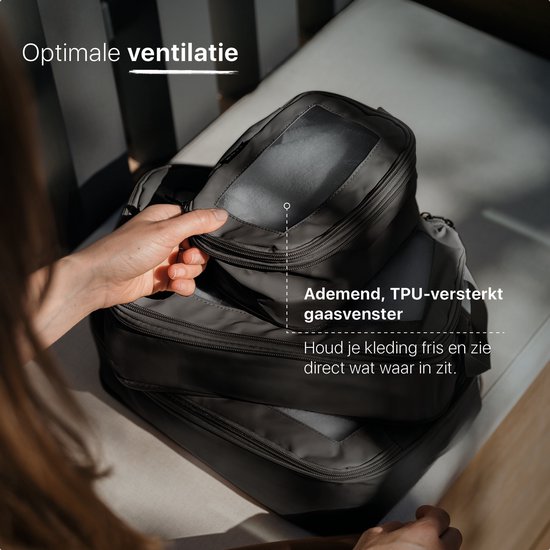 Een hand die een grijze ONYX packing cube oppakt met een ademend TPU-versterkt gaasvenster.