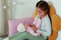 Meisje met vlecht houdt baby pop in roze pyjama vast. Baby Annabell.