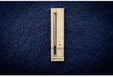Meater+ thermometer in houten houder, geplaatst op een donkere, getextureerde achtergrond.