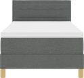 Donkergrijze boxspring met gestreept hoofdbord, wit matras en houten poten.
