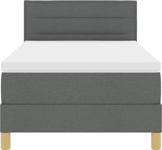 Donkergrijze boxspring met gestreept hoofdbord, wit matras en houten poten.