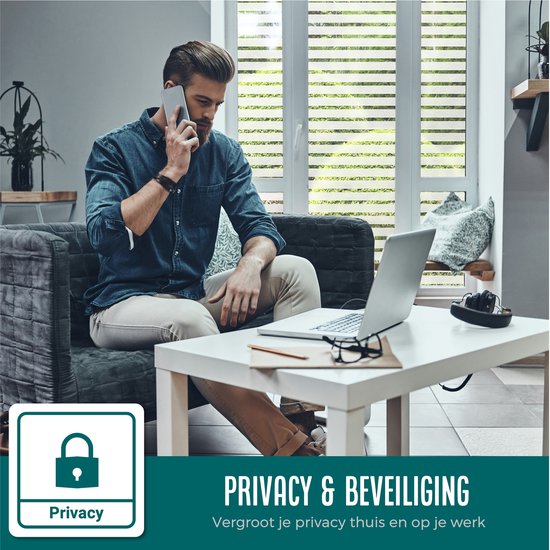 Man op de telefoon in woonkamer met laptop en raamfolie voor privacy. Tekst: 'Privacy & Beveiliging'.