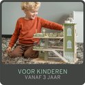 Jongen met blond haar speelt met de houten speelgoedgarage in retro groene kleur.