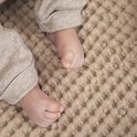 Babyvoetjes op een zandkleurige wafelstof.