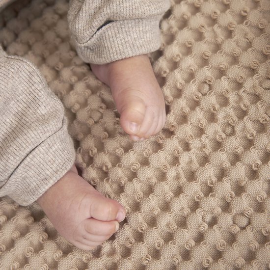 Babyvoetjes op een zandkleurige wafelstof.