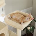 Een oranje gestreepte kitten ligt in een zachte, crèmekleurige hangmat op een krabpaal.