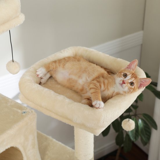 Een oranje gestreepte kitten ligt in een zachte, crèmekleurige hangmat op een krabpaal.