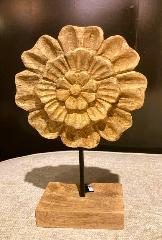 Houten bloemornament op een houten blok. Gedetailleerd gesneden bloem met veel lagen bladeren, op zwarte staander.